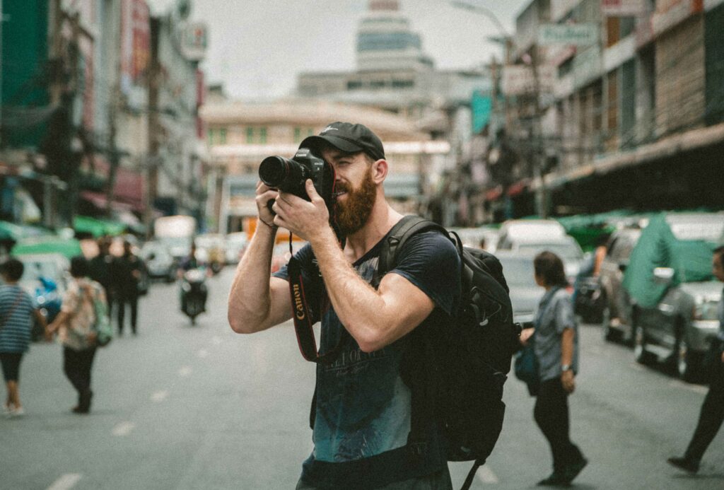 Travel photographer taking street photos with a DSLR camera in a busy urban city